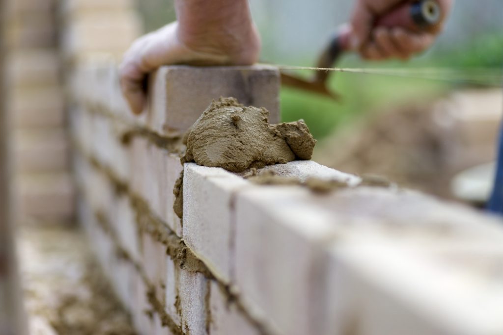 man laying bricks down, close up of mortar